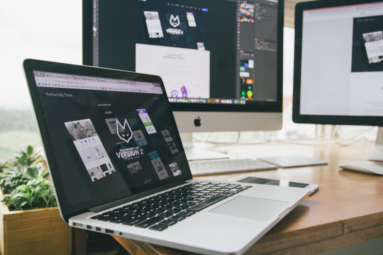 a laptop sitting on top of a desk with two monitors